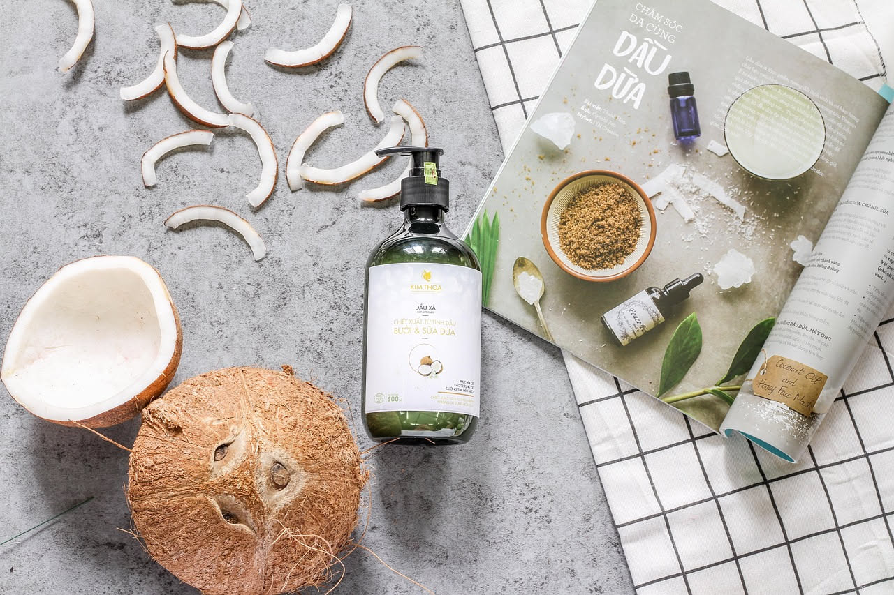 Balsamo naturale in vasetto di vetro circondato da erbe fresche, semi di lino e gocce d'acqua su sfondo bianco