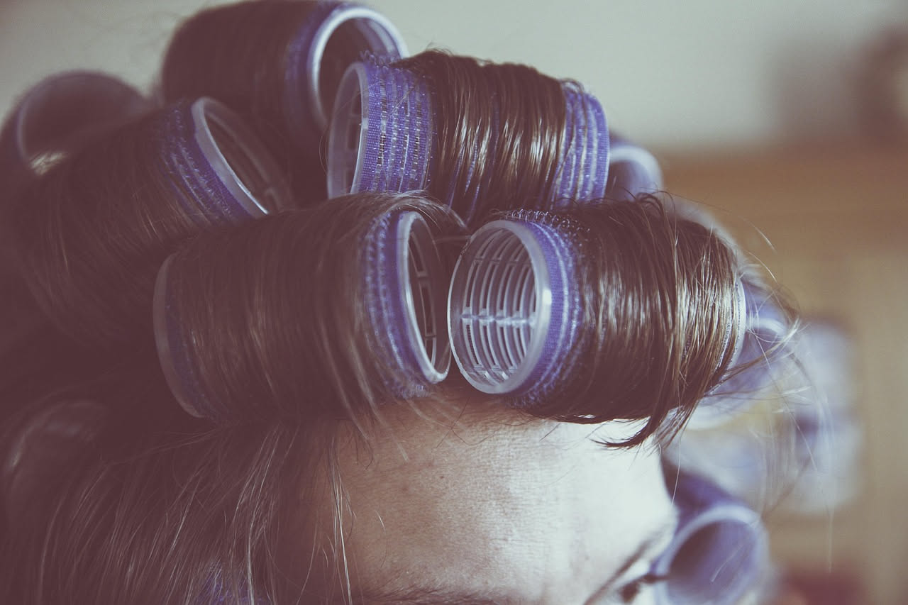 Una donna degli anni Venti con capelli ondulati e mossi tipici della permanente storica, fotografata in bianco e nero in studio.
